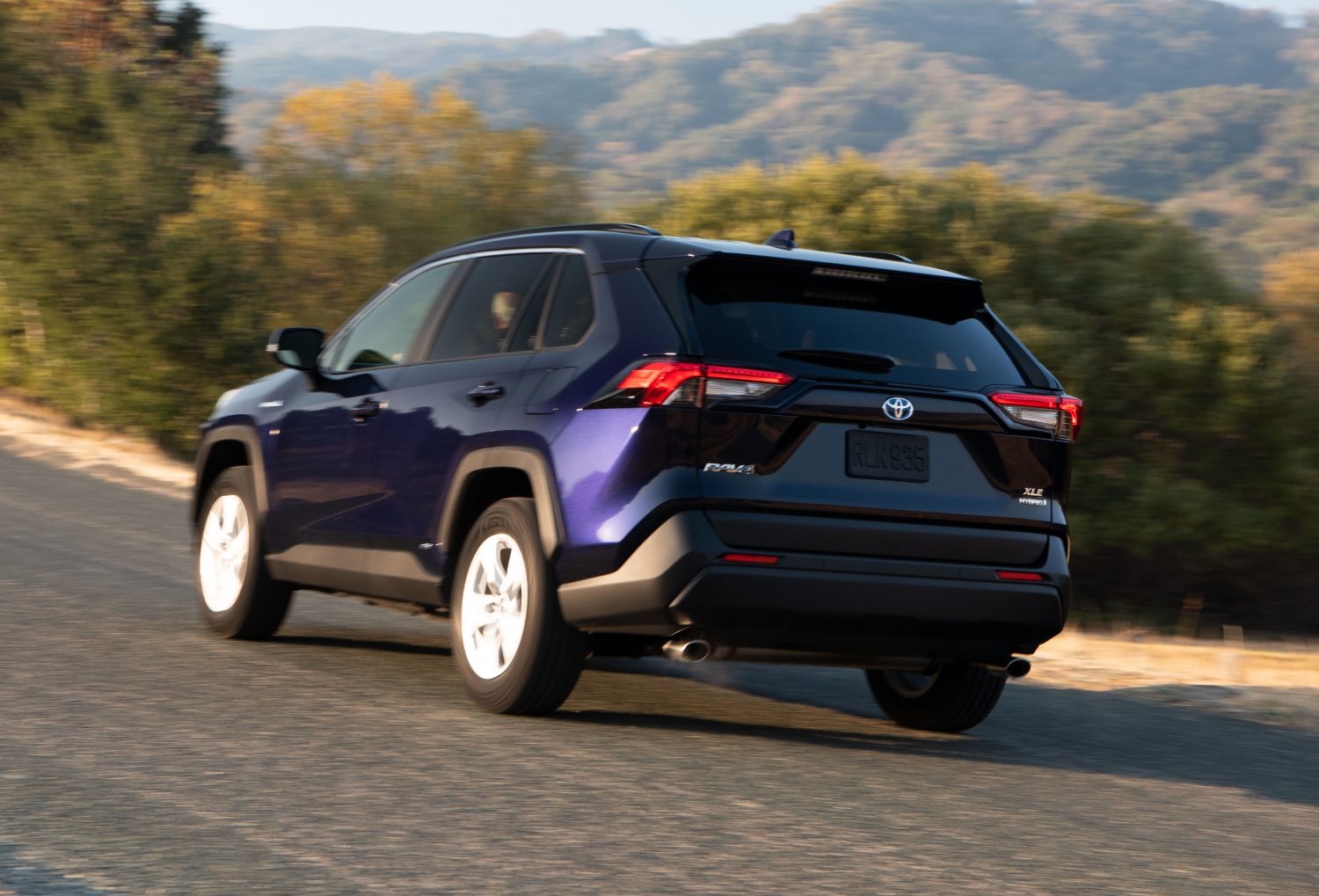 low left rear view of blueprint color rav4 driving on road