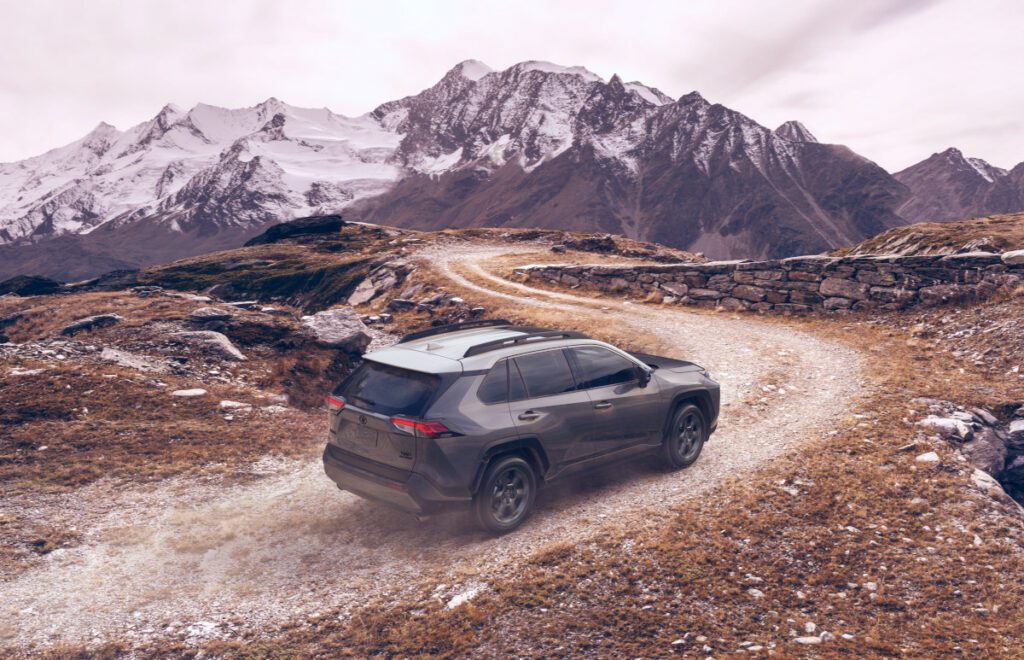 magnetic gray metallic rav4 off roading with snow capped mountains in background