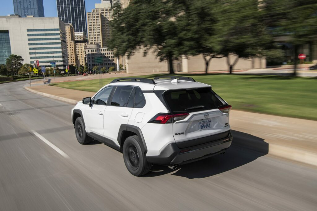 rav4 in ice cap color rear left view driving i city